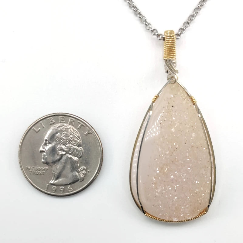 Wire-wrapped drusy agate pendant  next to a U.S. quarter on a white background