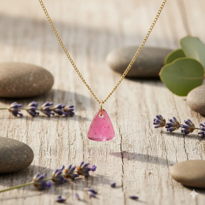 Necklace with a pink tourmaline pendant on a wooden surface with lavender and stones