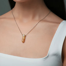 Close-up of a woman wearing a necklace with a Tangerine Quartz pendant featuring warm orange tones with natural inclusions