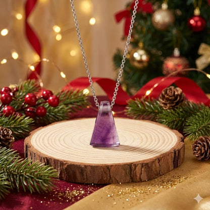 Necklace with a amethyst pendant on a wooden stand against a festive background with Christmas decorations.