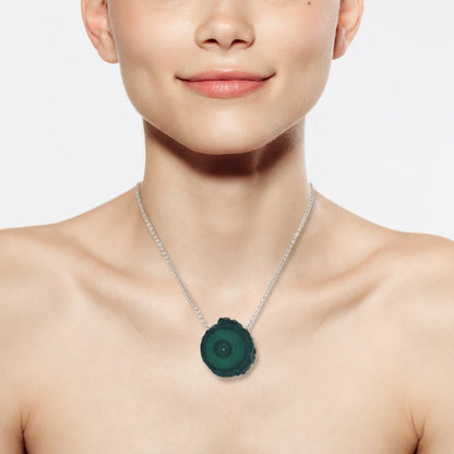 Close-up of a woman wearing a necklace with a Malachite Stalactite Slice pendant showcasing a natural cross-section of banded green malachite, highlighting concentric growth patterns