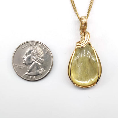 Wire-wrapped golden mica pendant next to a U.S. quarter on a white background