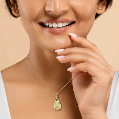 Close-up of a woman wearing a necklace with a teardrop-shaped Golden Mica pendant showcasing shimmering golden layers that reflect light, with 14K Gold Filled Wire wrapped and bail