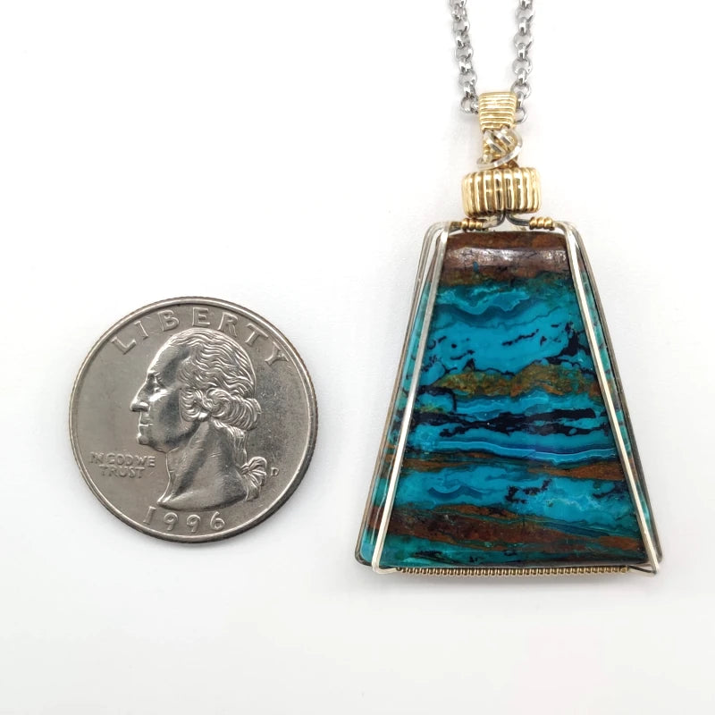 Wire-wrapped chrysocolla pendant necklace next to a quarter on a white background