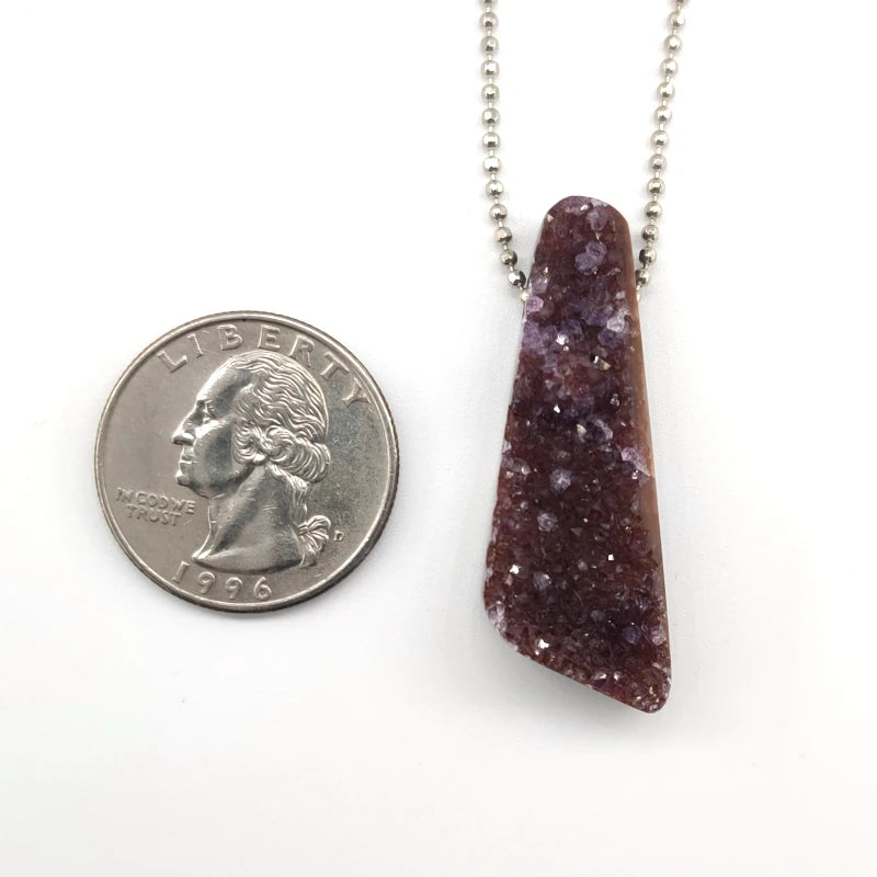 Necklace with a drusy amethyst pendant next to a quarter for scale on a white background