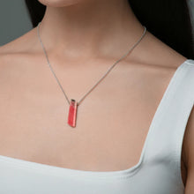 Close-up of a woman wearing a necklace with a Rhodochrosite pendant displaying soft pink to rose-red tones with natural banding