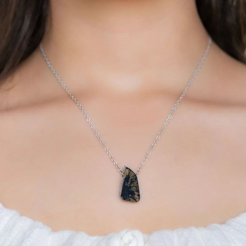 Close-up of a woman wearing a necklace with a Rutilated Quartz pendant showcasing golden needle-like inclusions within clear quartz