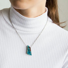 Close-up of a woman wearing a necklace with a triangular Drusy Chrysocolla pendant combines vibrant turquoise-green tones with a sparkling drusy surface