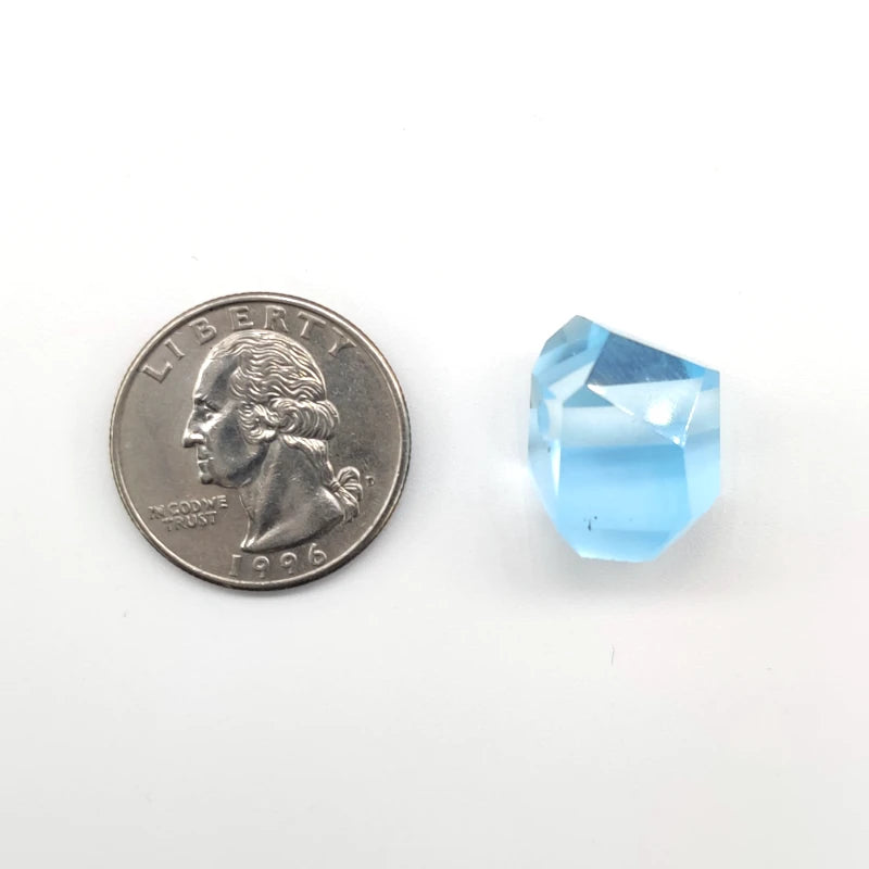 Clear blue topaz next to a U.S. quarter coin on a white background