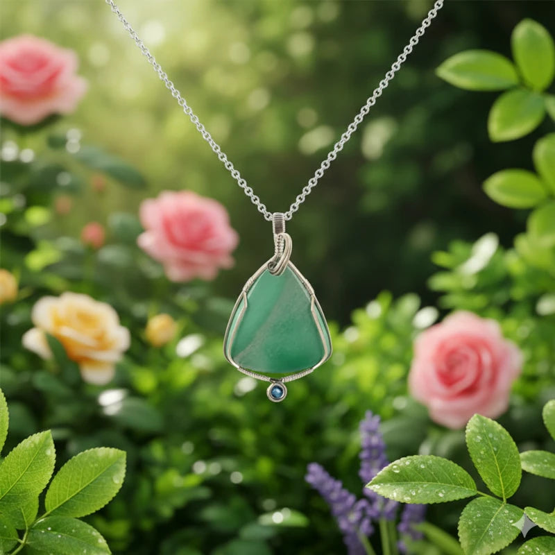 Green teardrop pendant necklace with a blue gemstone against a floral background