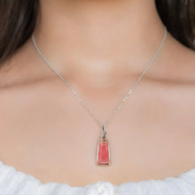 Close-up of a woman wearing a necklace with Rhodochrosite pendant set in sterling silver wire wrap and bail.
