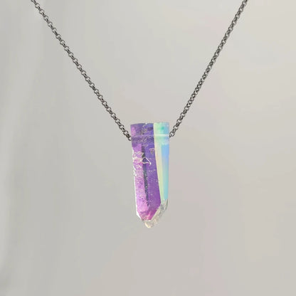 Neckless with a Angel Aura Quartz pendant featuring a polished crystal point treated to reveal a shimmering display of iridescent colors, shifting between soft purples, blues, and hints of gold, on a white background.