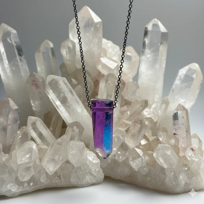 Necklace with a angel aura quartz pendant in front of crystal formations