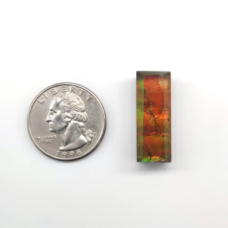Ammolite stone pendant next to a quarter on a white background