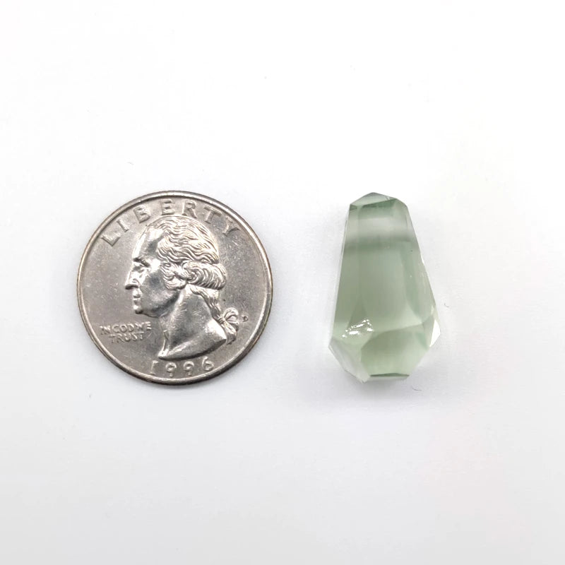 Green crystal next to a U.S. quarter on a white background