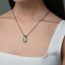 Close-up of a woman wearing a Necklace with a faceted Prasiolite pendant featuring soft green tones