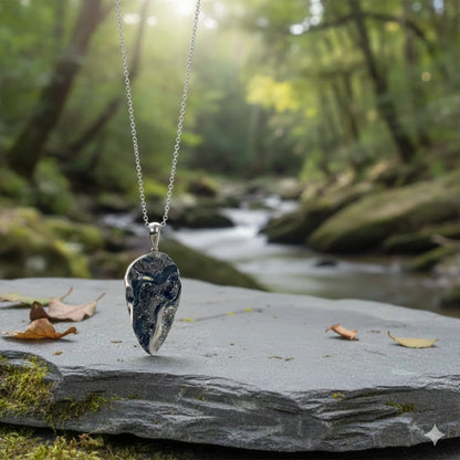 Necklace with a drusy pyritized ammonite fossil pendant on a rock in a forest setting
