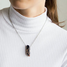 Close-up of a woman wearing a necklace with a Dryhead Agate pendant showcasing earthy tones with intricate banding patterns