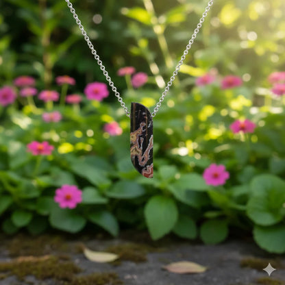 Necklace with a dryhead agate pendant in front of pink flowers