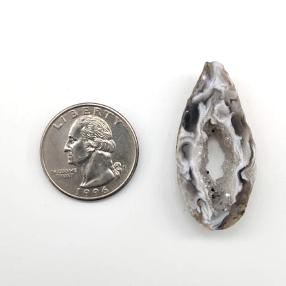 Oco geode stone pendant next to a quarter on a white background