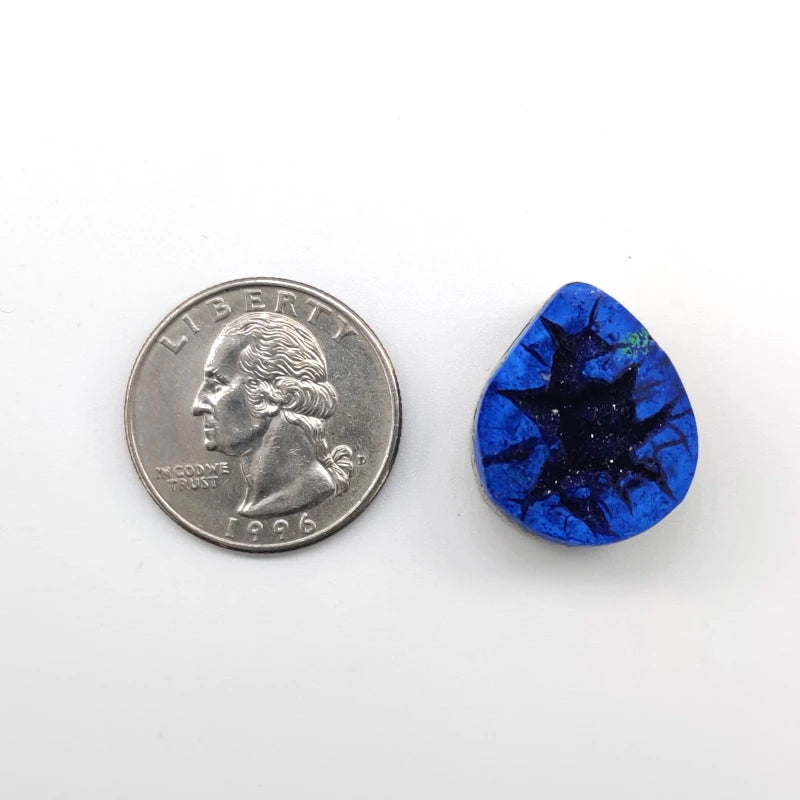 Teardrop-shaped azurite geode pendant next to a quarter on a white background