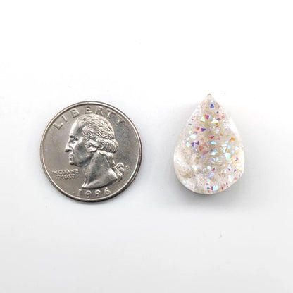 Teardrop-shaped angel aura pendant next to a quarter on a white background