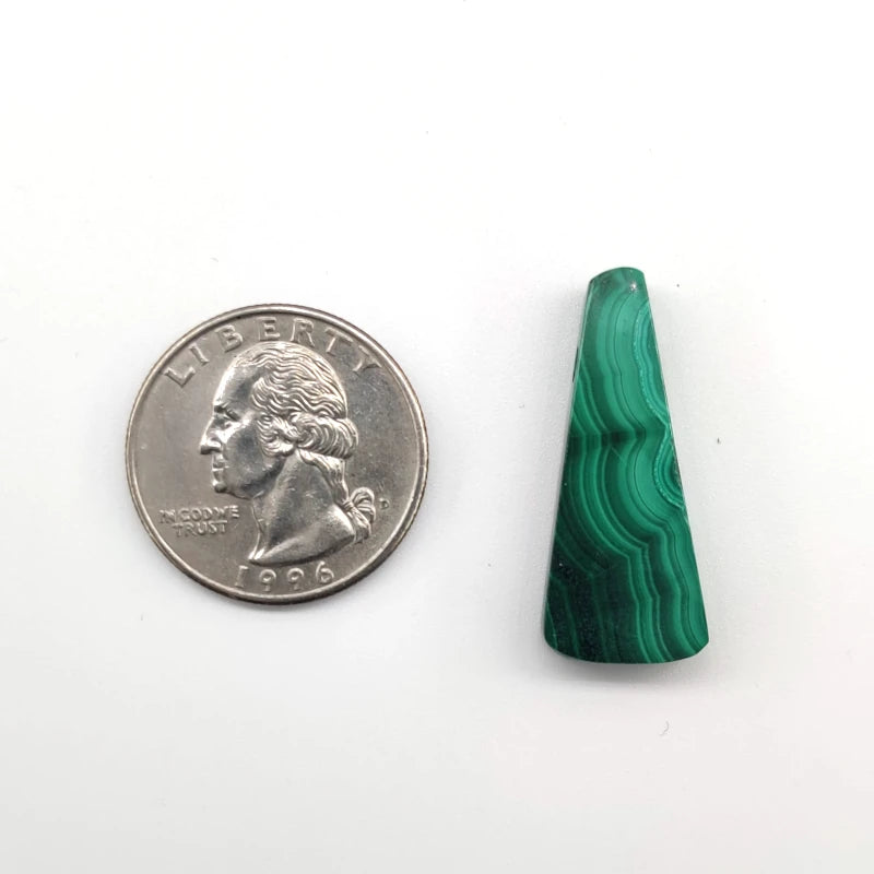 Green malachite stone next to a U.S. quarter on a white background
