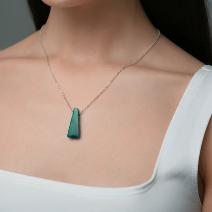 Close-up of a woman wearing a necklace with a Malachite pendant highlighting rich green hues with distinctive natural banding