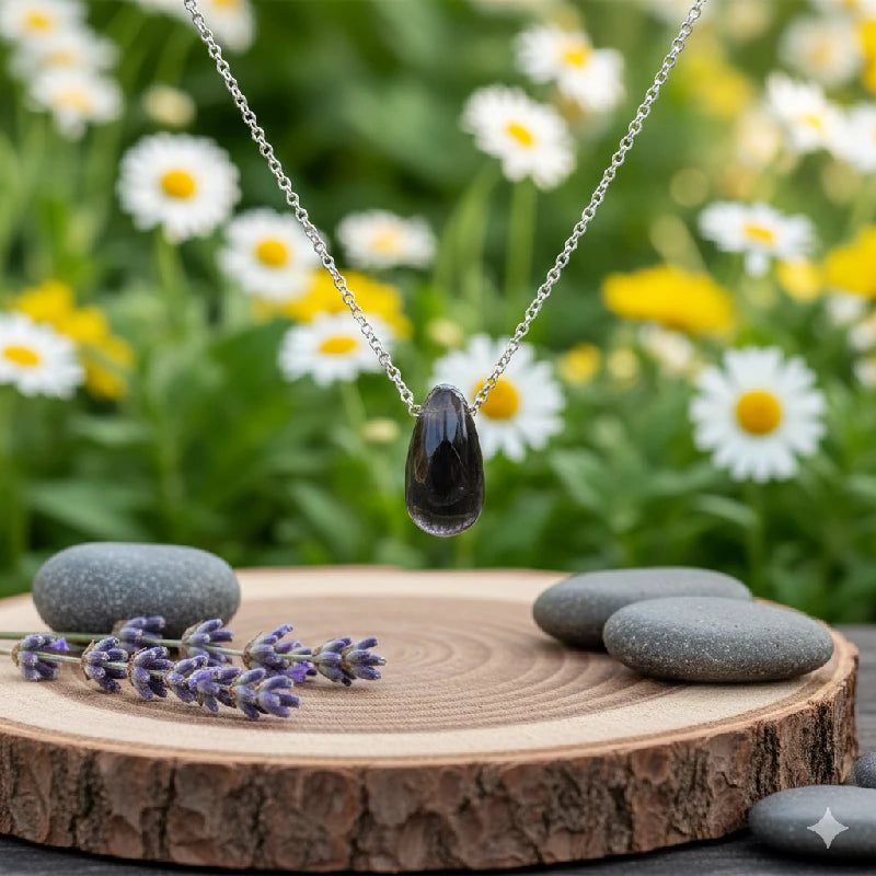 Necklace with a labradorite pendant on a wooden platform with stones and lavender, against a natural background of flowers.