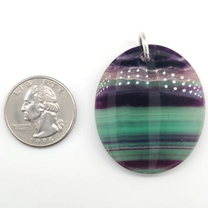 Fluorite pendant next to a quarter for size comparison on a white background