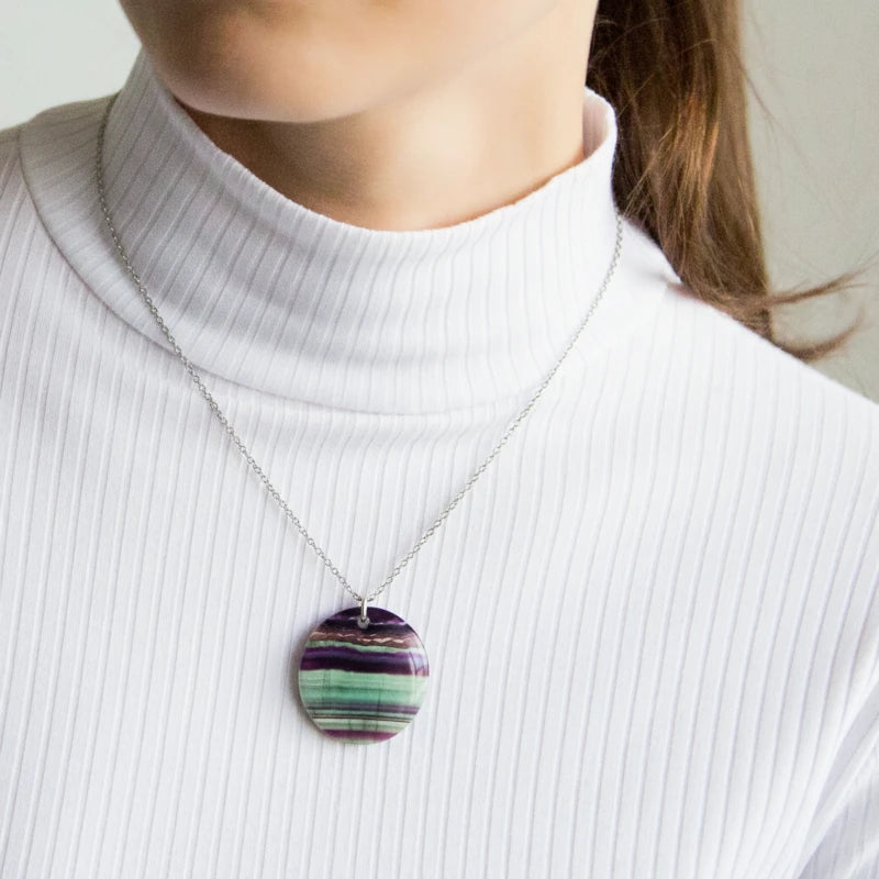 Person wearing a fluorite pendant necklace against a neutral background