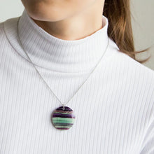 Person wearing a fluorite pendant necklace against a neutral background