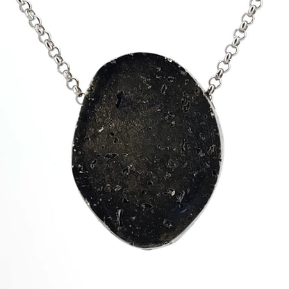 Back of a pyrite pendant on a chain against a white background