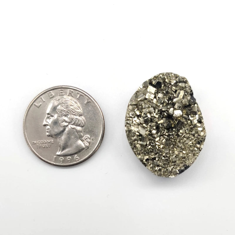 Pyrite stone next to a U.S. quarter on a white background