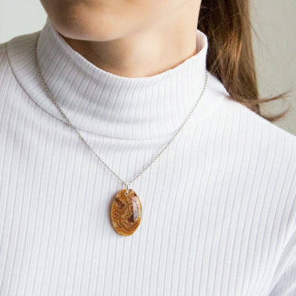 Person wearing a necklace with a agate pendant on a plain background