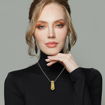 Woman wearing a yellow quartz pendant necklace against a gray background