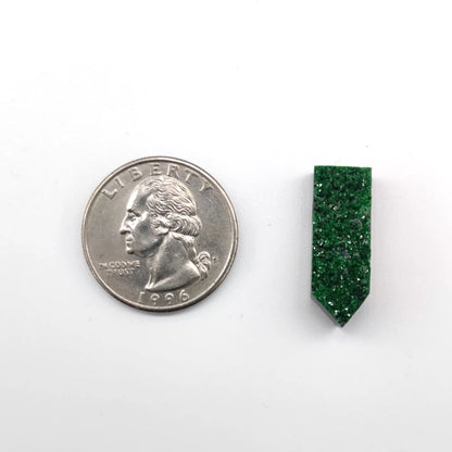 Green gemstone pendant next to a U.S. quarter on a white background