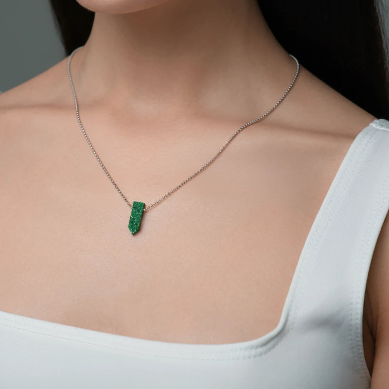 Necklace with a green pendant worn by a person against a neutral background