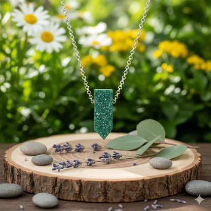 Green pendant necklace on a wooden stand with flowers in the background