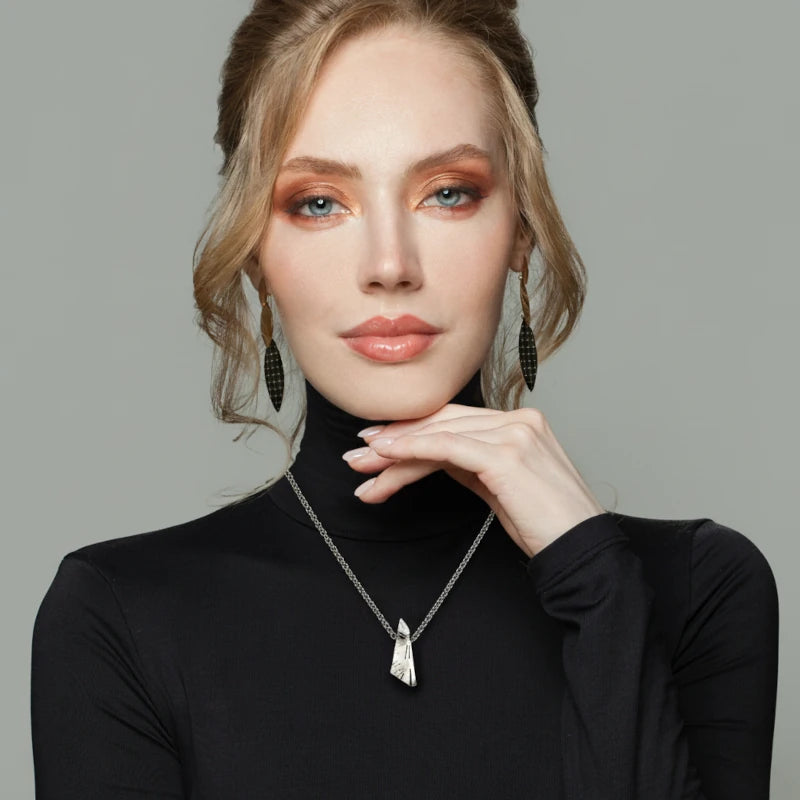 Woman wearing a quartz pendant  necklace  against a gray background