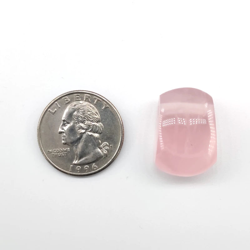 Rose quartz crystal next to a U.S. quarter on a white background