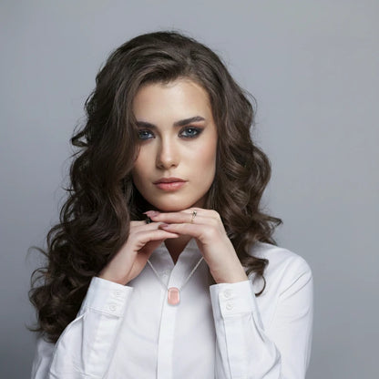 Woman wearing a rose quartz pendant necklace against a gray background
