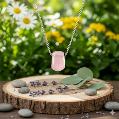 Rose quartz pendant on a wooden slice with flowers in the background