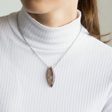 Necklace with a dryhead agate pendant worn by a person in a white turtleneck.