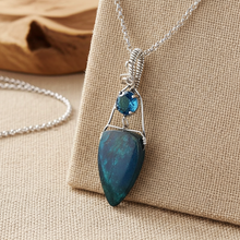 Necklace with apatite and blue topaz  pendant on a beige fabric background